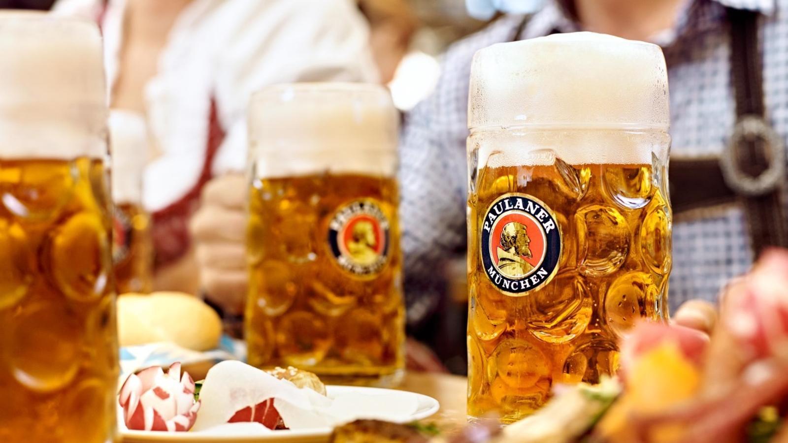 Jarras de cerveza Paulaner con espuma en un ambiente bávaro